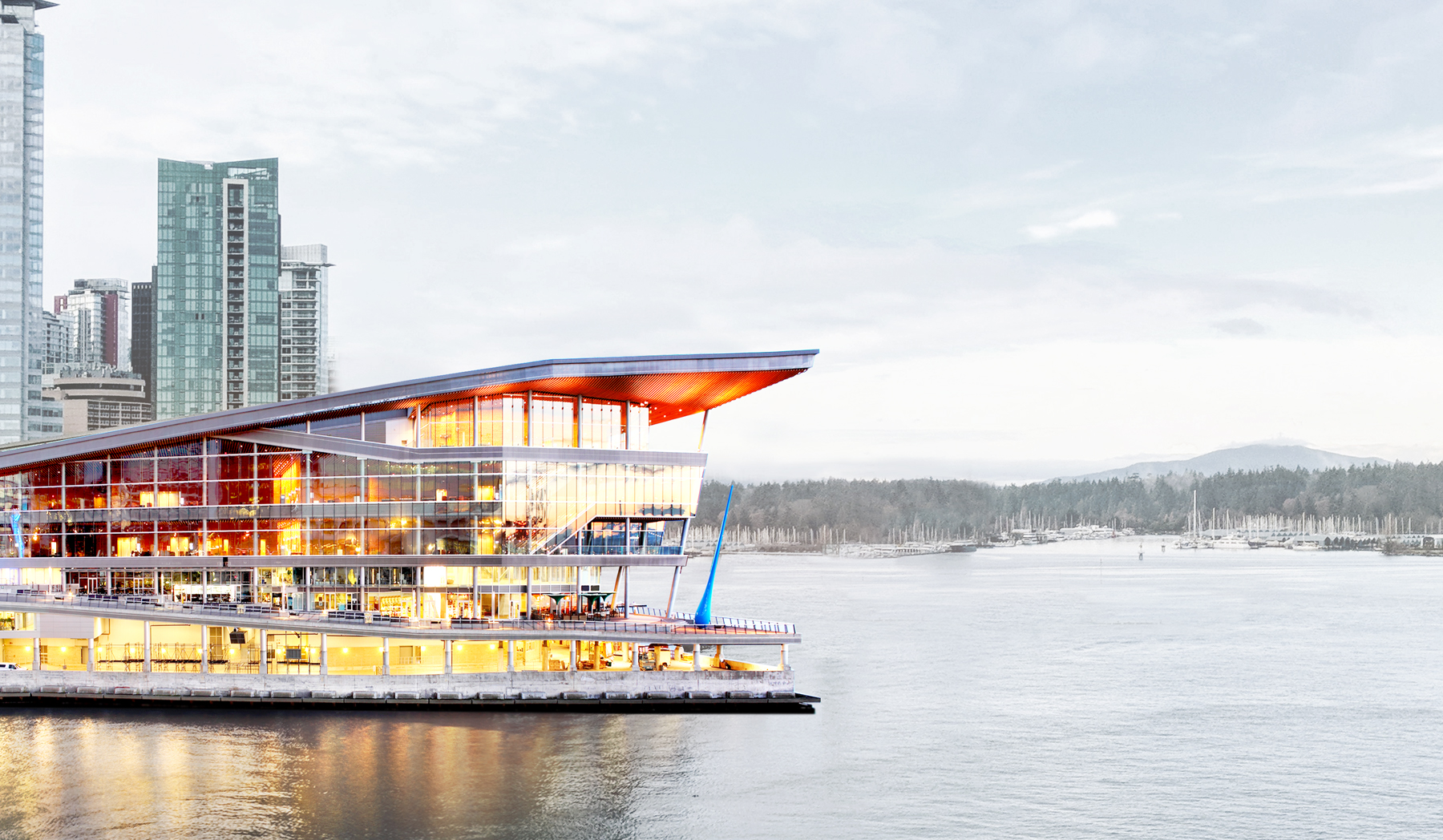 The Vancouver Convention Centre lies surrounded by buildings, greenery, and a body of water.